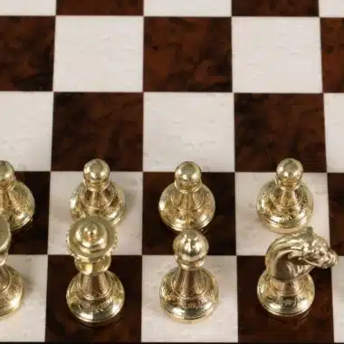 Vue plongeante sur les pions dorés en métal alignés sur l'échiquier