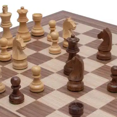 Pièces d'échecs en bois d'acacia disposées sur l'échiquier en noyer