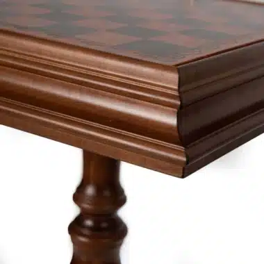 Table échiquier en bois, gros plan sur le coin mouluré et le pied tourné