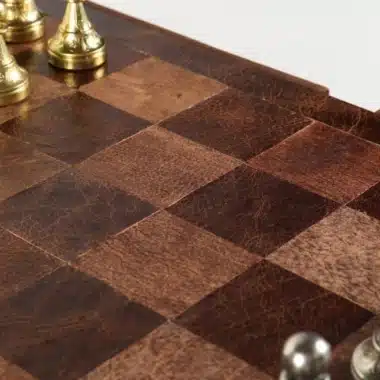 Gros plan sur l'échiquier en cuir véritable à damier marron et pièces dorées
