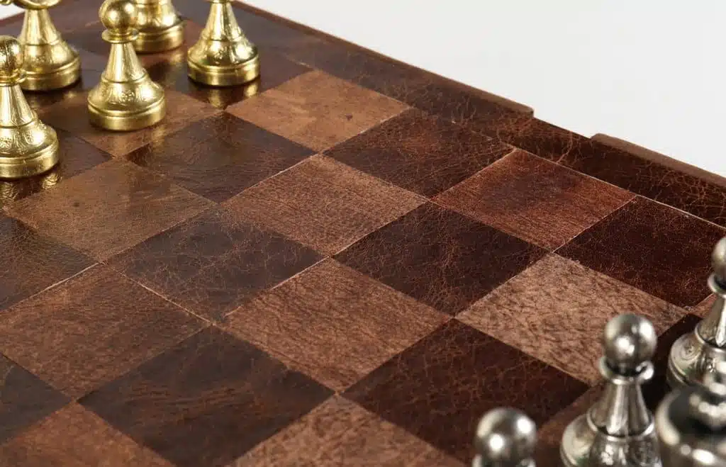 Gros plan sur l'échiquier en cuir véritable à damier marron et pièces dorées